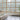 Spacious interior staircase with large grid windows, modern railing, and potted plant.
